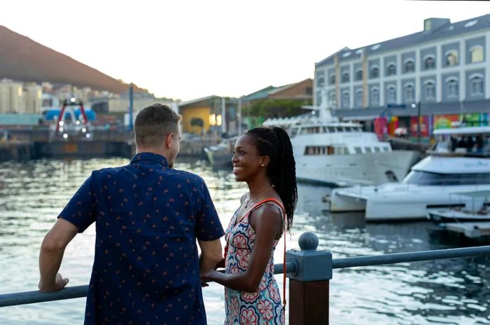 A couple smiles together at a waterfront filled with numerous docked boats