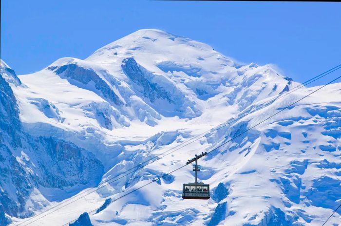 A cable car glides past the snow-capped peak of Mont Blanc