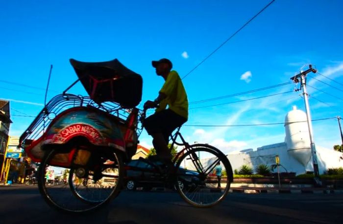 A traditional rickshaw navigates the streets of Indonesia.