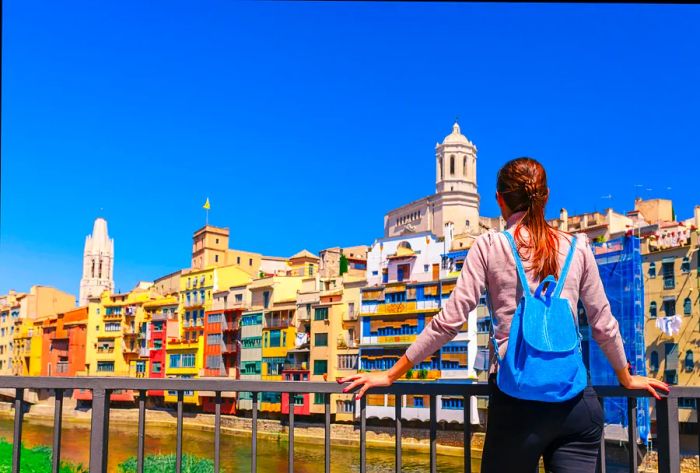 A woman gazing at the vibrantly painted buildings in Girona, Spain