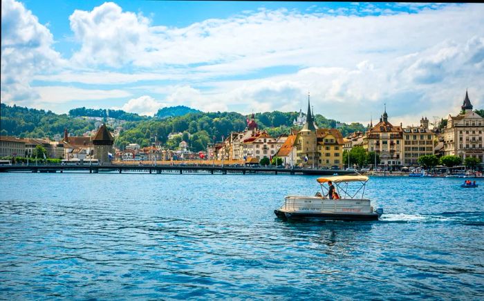 A couple enjoys a small boat ride on a lake, framed by the picturesque cityscape nearby.