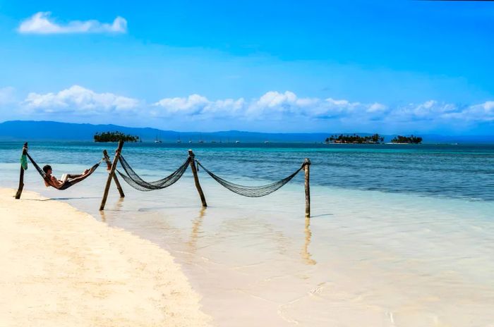 A tourist unwinding in a hammock on the stunning Dinogo Beach in the Caribbean San Blas Islands, within the politically autonomous Guna territory in Panama.