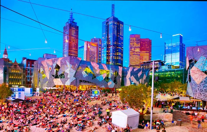 People enjoy relaxation in a city square illuminated at dusk