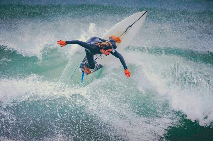 A surfer practices in the winter waters of Peniche, navigating the challenging waves. Peniche has emerged as one of Portugal’s top surfing destinations, featuring a variety of beaches that cater to different skill levels.