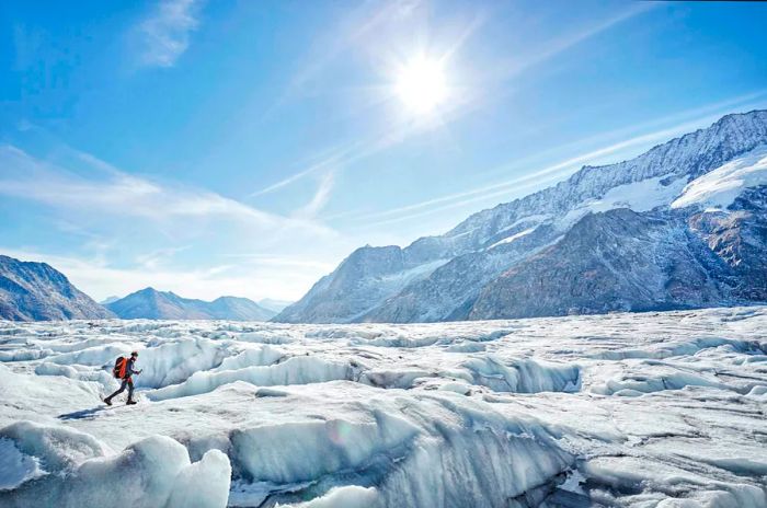 A hiker explores a vast glacier beneath the shining sun