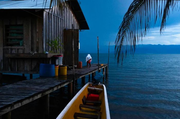 A child from Cayo de Agua Island retrieves laundry from outside, Bocas del Toro, Panama