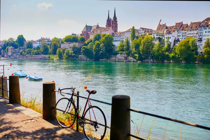 A picturesque view of the Rhine embankment with people enjoying a swim in the river in Basel, Switzerland.