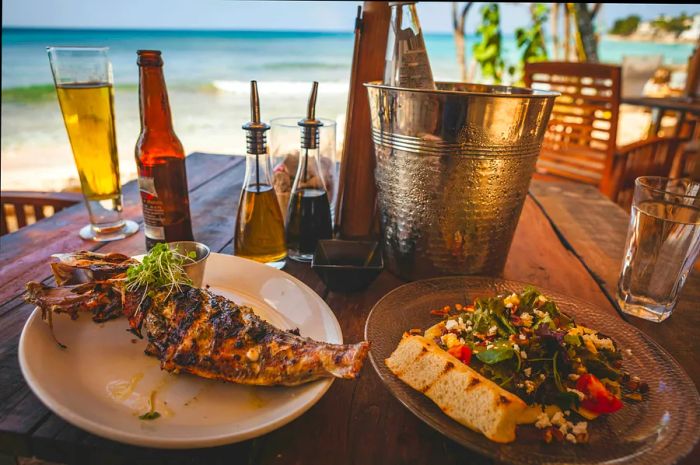 A beachside table in Barbados set for a lunch of grilled fish and salad