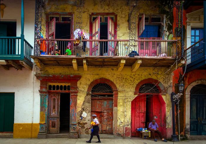 A woman strolls through the historic Casco Viejo district of Panama City, while a vendor takes a nap nearby.