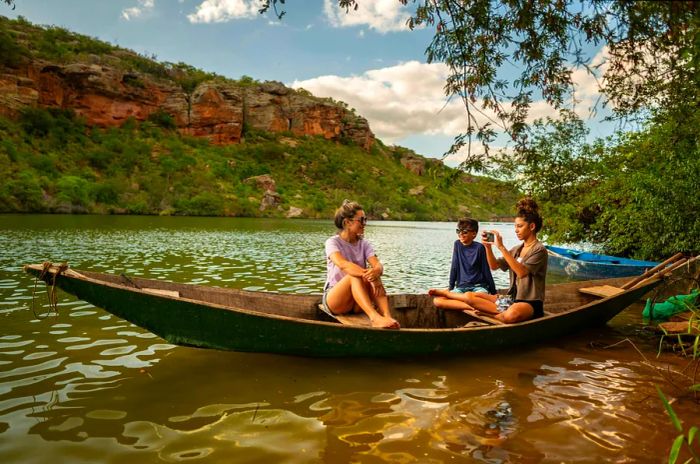 Three young teens capture memories from a small canoe on a river