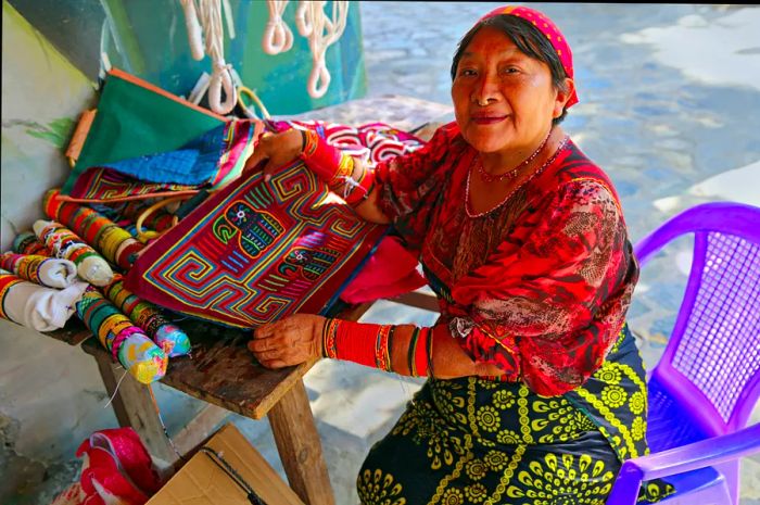 A vibrant Guna artist crafts traditional art at her workspace in the stunning Rainforest Mountain village of El Valle de Anton, Panama. The Guna people are the indigenous inhabitants of Panama.