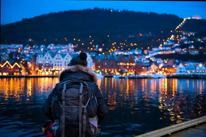 A man in a parka stands at the harbor at night, Bergen, Norway