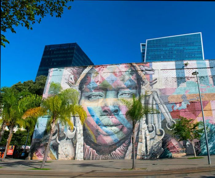 A mural depicting a woman's face spans the entire side of a building.