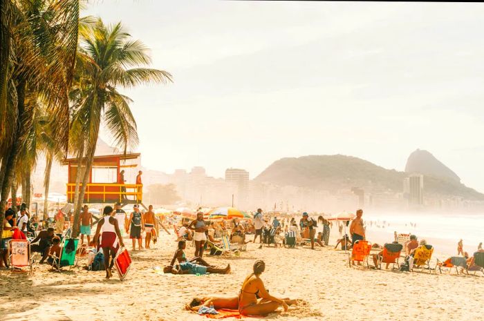 Visitors enjoying the sun and lounging at the iconic Copacabana beach in Rio de Janeiro, Brazil