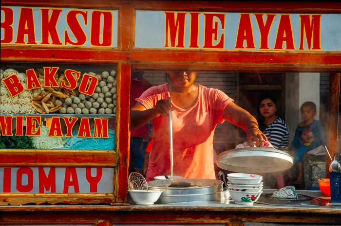 A woman prepares meatball soup at a street stall in Ubud