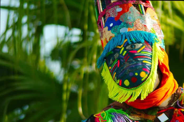 A masked performer dons a vibrant headdress.