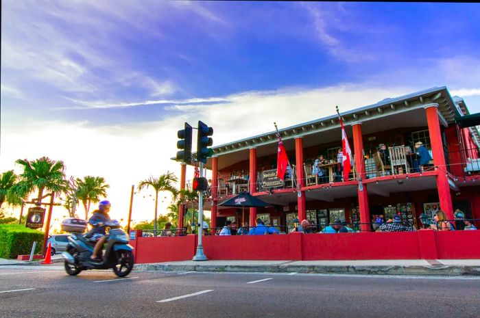 A motorbike speeds past a bustling restaurant.