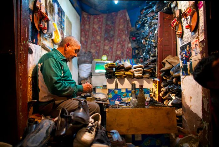 A man stitches leather shoes by hand.