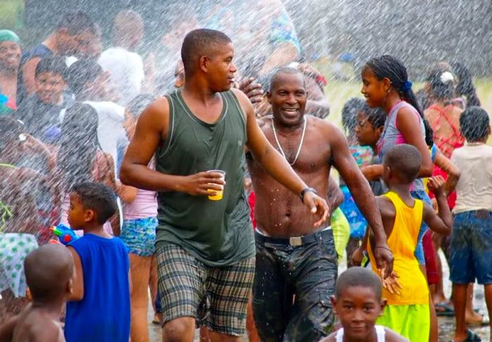 A lively crowd is doused with water at a vibrant street festival.