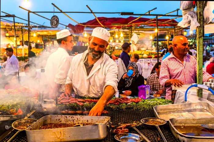 A vendor at a food stall in Jemaa el-Fnaa, the bustling heart of Marrakesh, Morocco. Street food stalls in Marrakech’s Djemaa el Fna square.