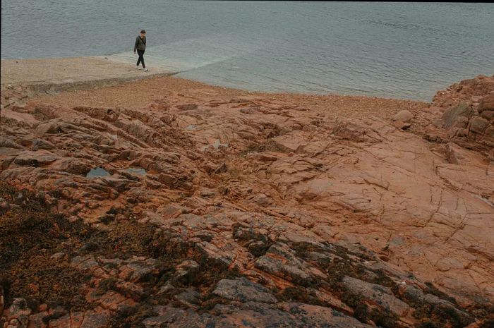 A woman hiking along the pink granite coast of Ile de Bréhat