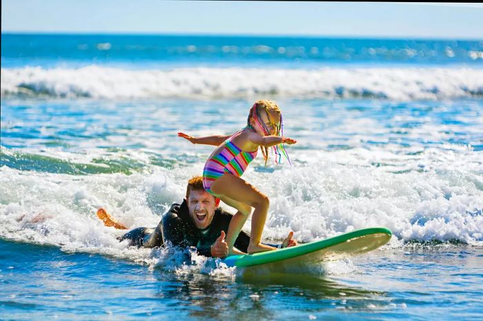 Young surfer learning to ride a wave with an instructor at a surf school in Bali