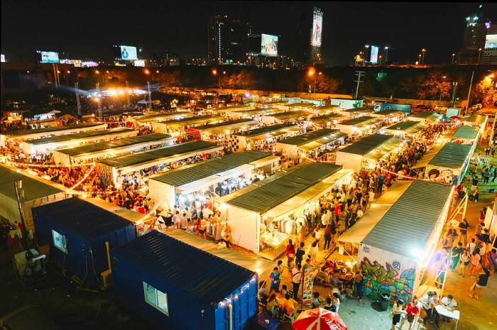 From above, the stalls of Artbox Night Market in Bangkok radiate with light as vendors showcase their goods.