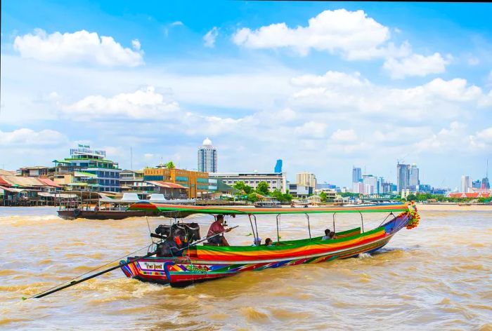 A chartered long-tail boat gliding along the Chao Phraya River in Bangkok