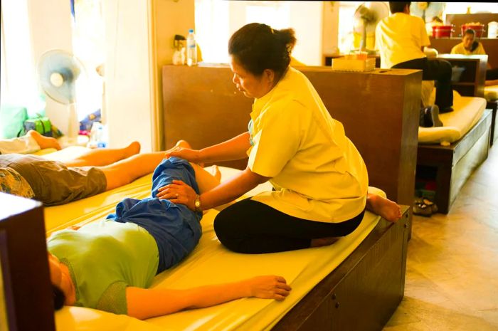 A Thai masseuse provides a massage at Wat Po, Ko Ratanakosin in Bangkok, Thailand.