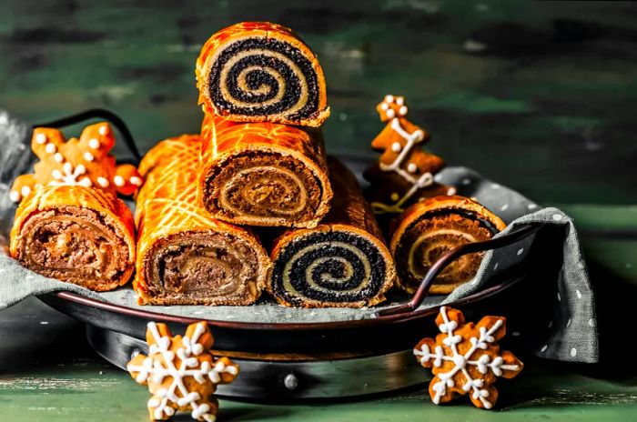 A stack of Hungarian beigli cake reveals its swirling filling, adorned with festive Christmas decorations.