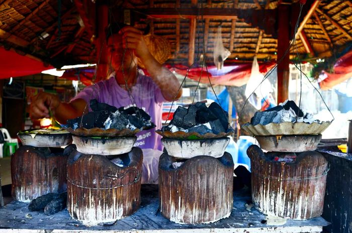 A chef prepares the Filipino treat known as Bibingka, made from ground glutinous rice in clay pots.