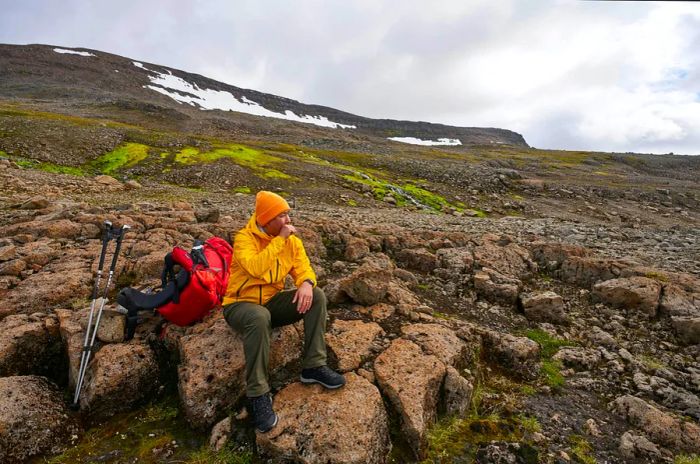 A hiker rests on a rock while taking a break in Hornstrandir, Iceland.