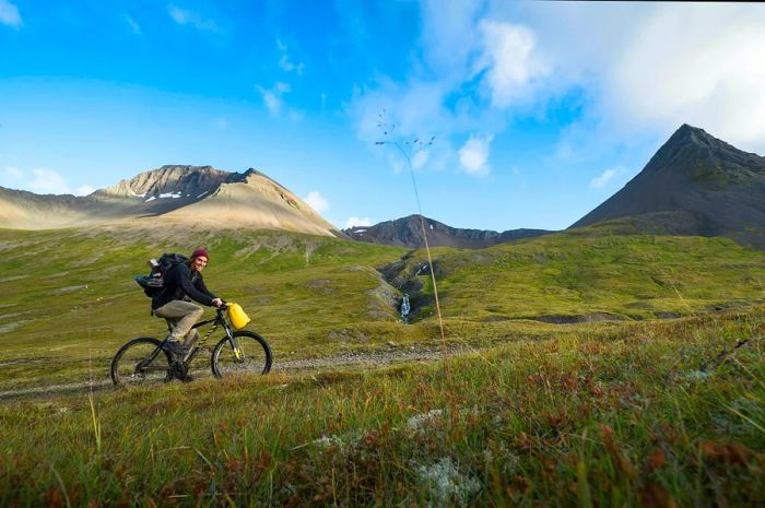 A cyclist ascends the Kirkjubolsdalur path towards Kaldbakur mountain in the Westfjords.