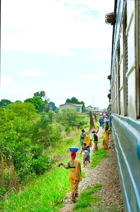 Women selling beverages and snacks through the windows of a train during a stop in Tanzania