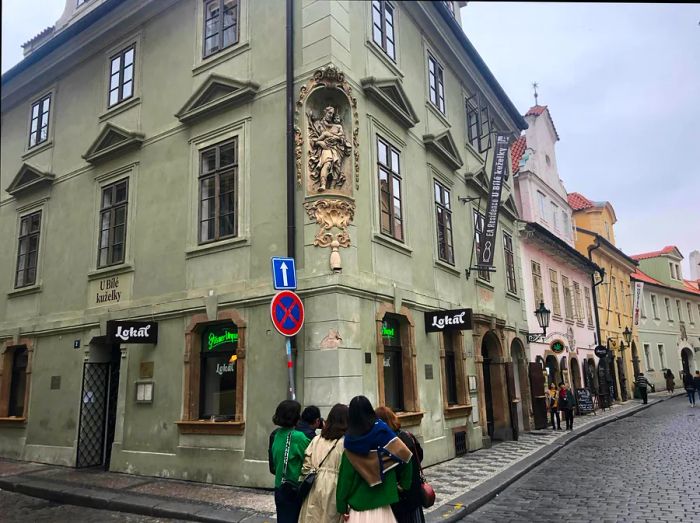 A group of tourists taking photos in front of the exterior of Lokál U Bílé kuželky