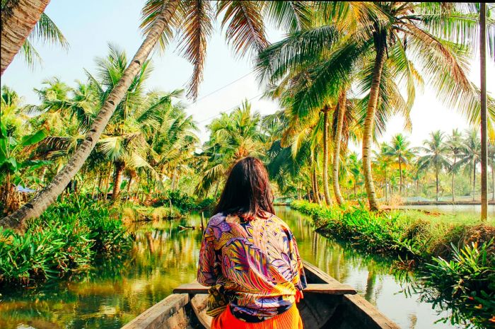 A young woman paddles her kayak through the serene backwaters of Monroe Island in Kollam District, Kerala, South India.