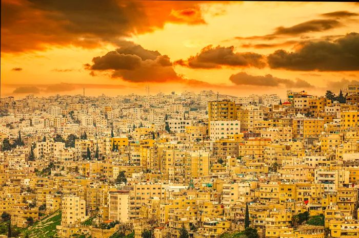 A sweeping view of dense apartment buildings perched on a hillside in Amman, Jordan, at sunset