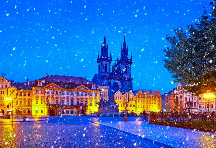 Snowy nighttime view of the Church of Our Lady Before Tyn illuminated against the winter sky