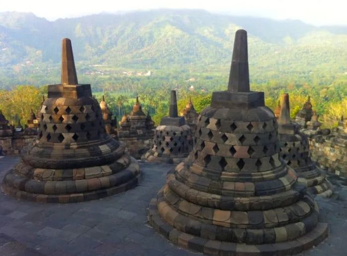 A view of Borobudur in Central Java, framed by treed hills in the background