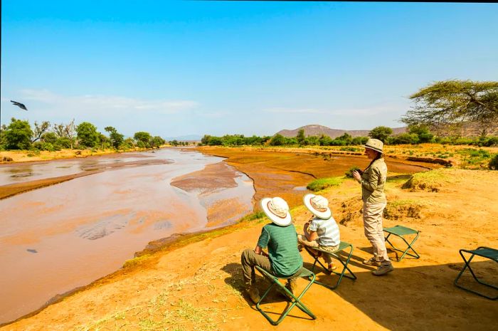 A mother and her children enjoying views of the Ewaso Nyiro River during an African safari in Samburu, Kenya