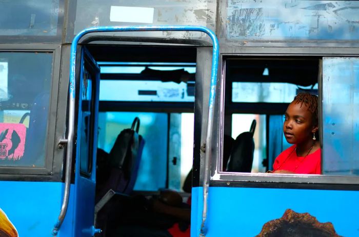 A woman gazes out the window of a bus, watching the road ahead.