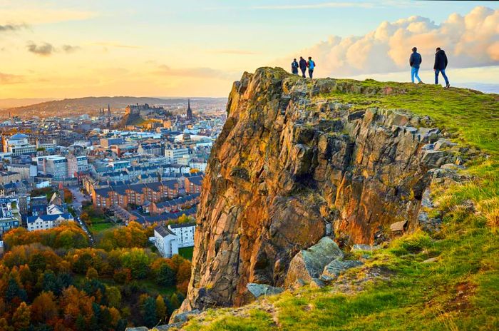 A group of individuals walking along a cliff edge, overlooking the beauty of Edinburgh