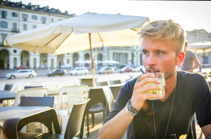 A man with blonde hair enjoys an aperitif at a bar in Turin.