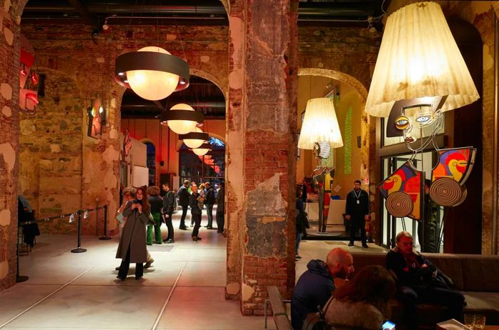 The interior of Officine Grandi Riparazioni buzzes with people exploring modern art displays.