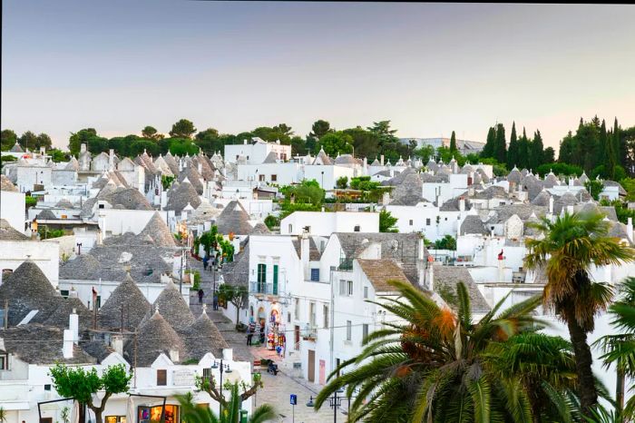 A view of Alberobello's Rione Monti district, featuring its iconic trulli—traditional round white houses—bathed in the glow of dusk.