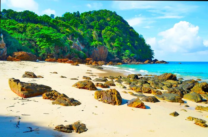 A secluded beach dotted with rocky boulders.