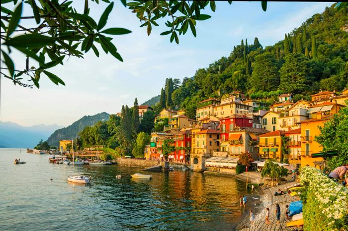 The charming village of Varenna, nestled along the shores of Lake Como, is characterized by its colorful buildings right at the water’s edge and lush green forests in the backdrop.