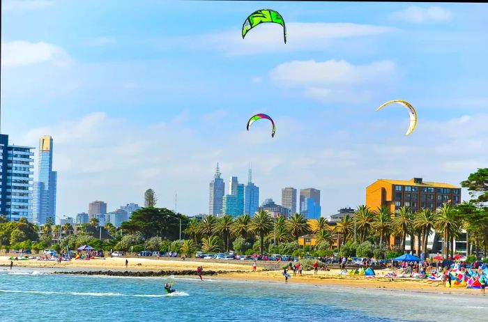 Kitesurfers glide over the waves at a beach near the city on a bright, sunny day