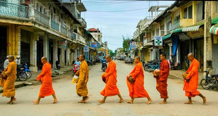 Monks in saffron robes head out to collect alms in Battambang