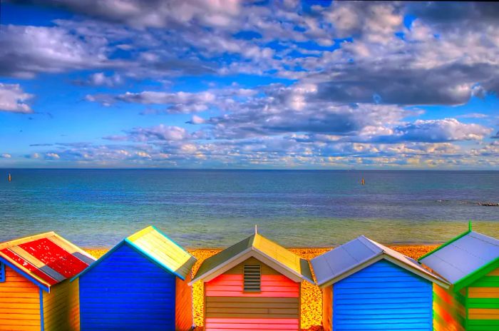 A vibrant row of beach huts stands facing the sea